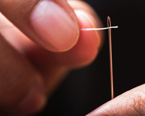 Closeup finger thread into the needle hole (Success began from a small thing); Shutterstock ID 160083596; Purchase Order: 261